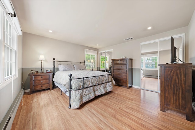 bedroom with light wood-style flooring, multiple windows, a baseboard heating unit, baseboards, and recessed lighting