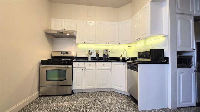 kitchen with appliances with stainless steel finishes, under cabinet range hood, a sink, dark countertops, and baseboards