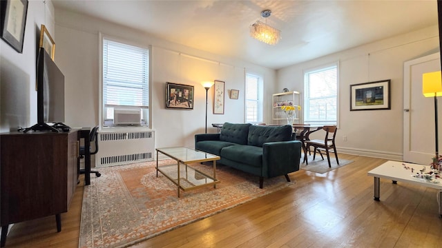living room with radiator, hardwood / wood-style flooring, cooling unit, and baseboards