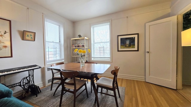 dining room with light wood finished floors, radiator heating unit, and baseboards
