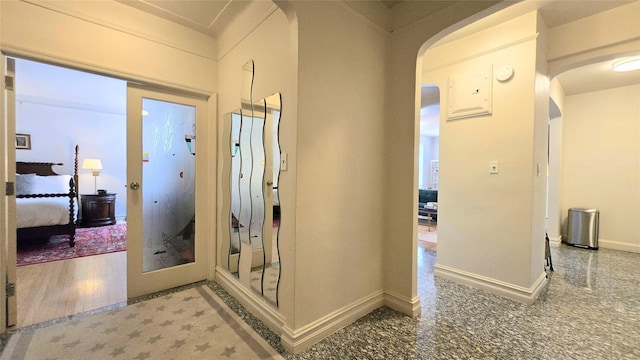 corridor featuring arched walkways and baseboards