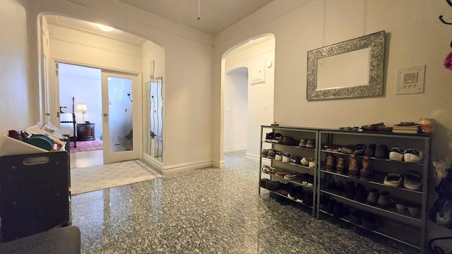 hallway with arched walkways, baseboards, and granite floors