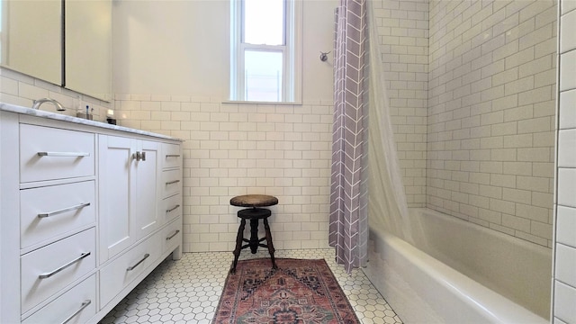 bathroom with tile walls, wainscoting, shower / bath combo with shower curtain, tile patterned flooring, and vanity