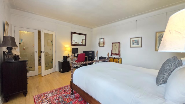 bedroom with french doors and light wood-style flooring