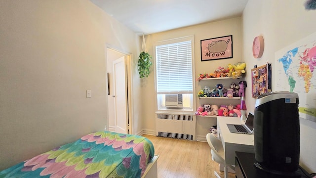 bedroom with radiator, light wood-style floors, and cooling unit