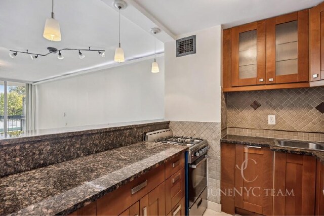 150-38 Union Tpke Unit 4K, Flushing, NY 11367 - kitchen with range with gas stovetop, brown cabinets, dark stone counters, and pendant lighting