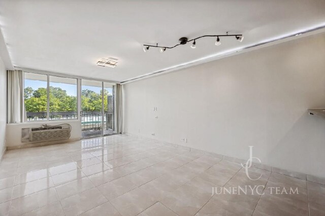 150-38 Union Tpke Unit 4K, Flushing, NY 11367 - tiled empty room featuring a wall mounted AC, floor to ceiling windows, and baseboards