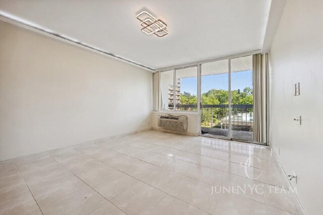 150-38 Union Tpke Unit 4K, Flushing, NY 11367 - tiled empty room featuring a wall mounted AC and a wall of windows