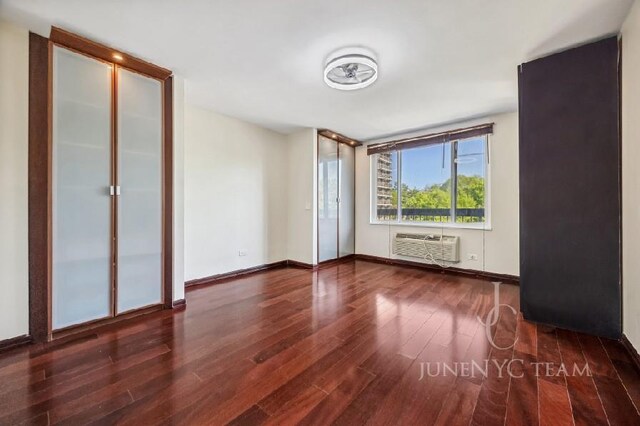 150-38 Union Tpke Unit 4K, Flushing, NY 11367 - spare room with wood finished floors, an AC wall unit, and baseboards