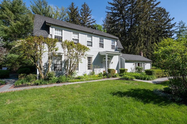 colonial inspired home with a front lawn and a chimney