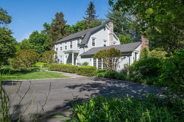 view of property exterior featuring a chimney, a gambrel roof, and a shingled roof