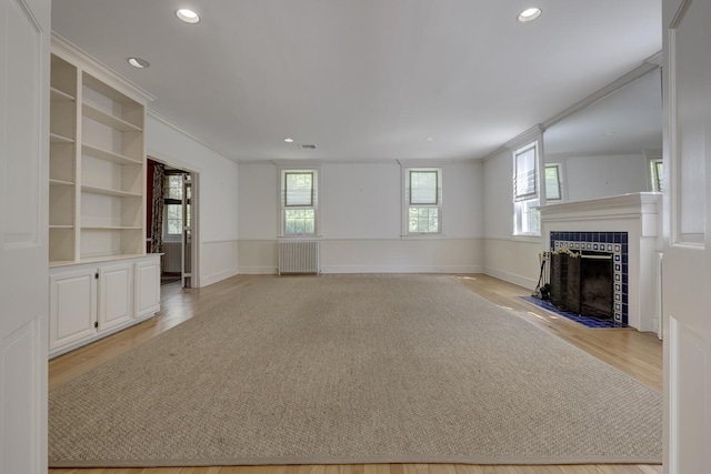 unfurnished living room featuring a tiled fireplace, light wood finished floors, recessed lighting, and baseboards