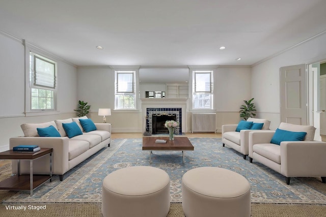 living room featuring radiator, ornamental molding, a fireplace, and recessed lighting