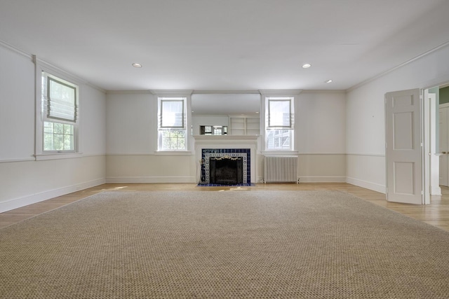 unfurnished living room featuring radiator, light wood-type flooring, plenty of natural light, crown molding, and baseboards