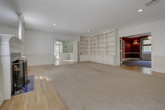 unfurnished living room with light wood-type flooring, crown molding, plenty of natural light, a fireplace with raised hearth, and baseboards