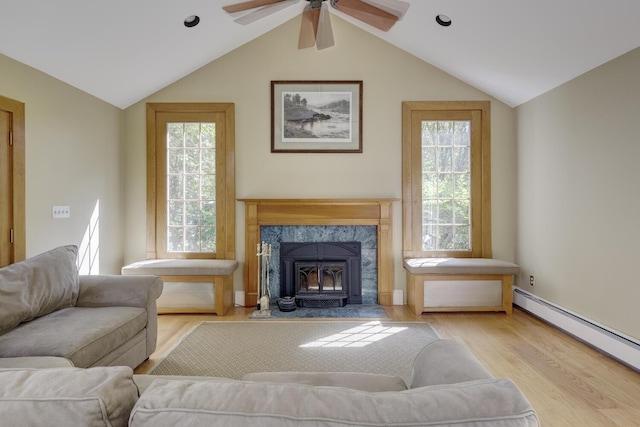 living area featuring a baseboard heating unit, lofted ceiling, wood finished floors, plenty of natural light, and a ceiling fan