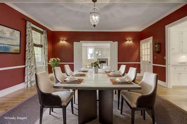 dining space featuring light wood finished floors, ornamental molding, baseboards, and a chandelier