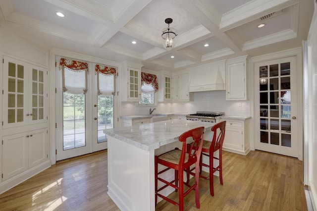 kitchen with french doors, custom exhaust hood, white cabinets, light wood-style floors, and tasteful backsplash