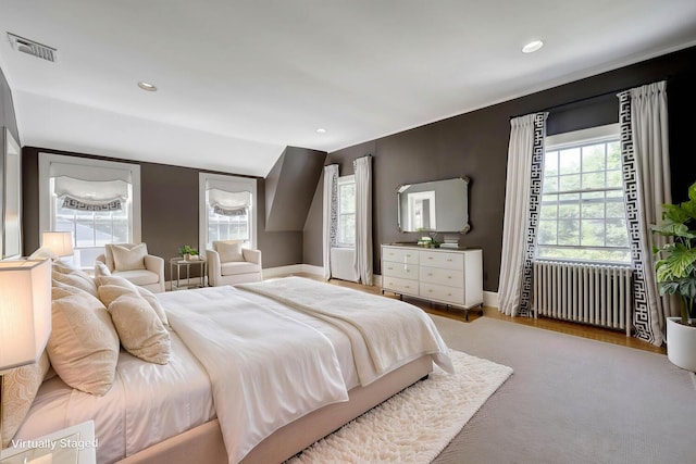 bedroom with radiator heating unit, multiple windows, baseboards, recessed lighting, and wood finished floors