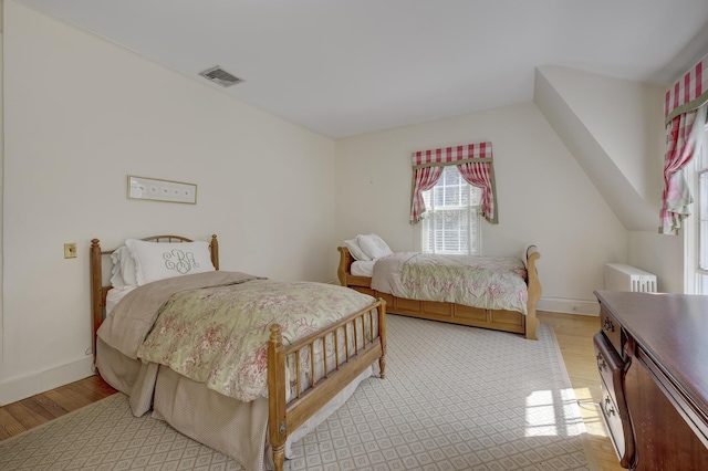 bedroom featuring light wood-style flooring, radiator, and baseboards