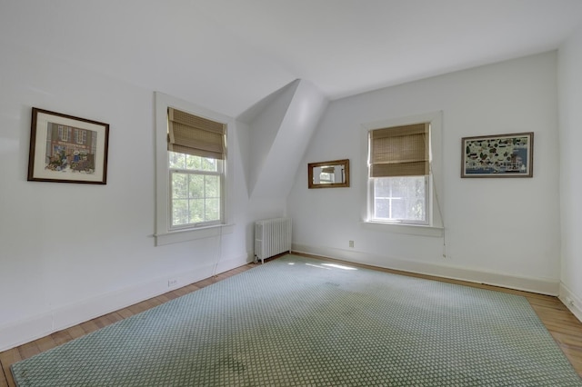 additional living space featuring radiator heating unit, light wood-type flooring, and baseboards
