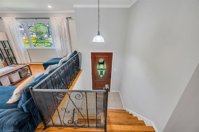entryway with crown molding, wood finished floors, and baseboards