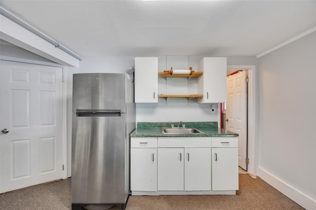 kitchen featuring freestanding refrigerator, a sink, light colored carpet, white cabinetry, and open shelves