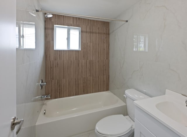 full bathroom featuring toilet, tile walls, vanity, and washtub / shower combination