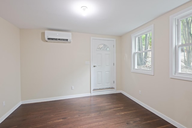 spare room featuring an AC wall unit, dark wood-style floors, and baseboards
