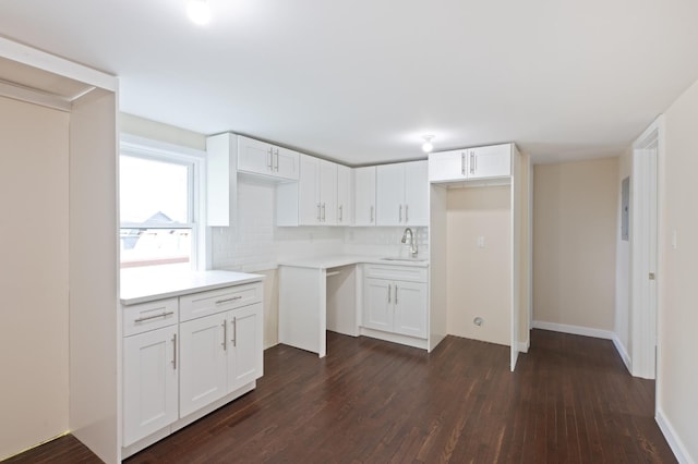 kitchen featuring dark wood finished floors, white cabinets, decorative backsplash, baseboards, and a sink