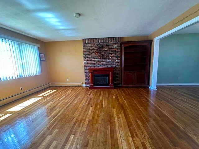 unfurnished living room with wood finished floors, a fireplace, baseboard heating, and baseboards