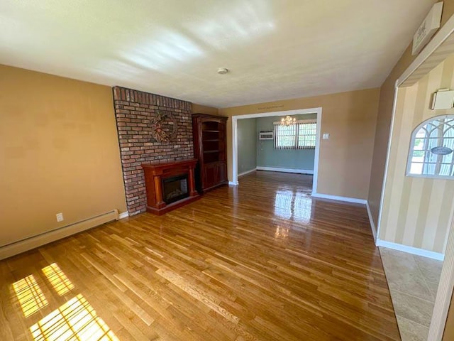 unfurnished living room featuring light wood-style flooring, a chandelier, baseboards, baseboard heating, and a brick fireplace