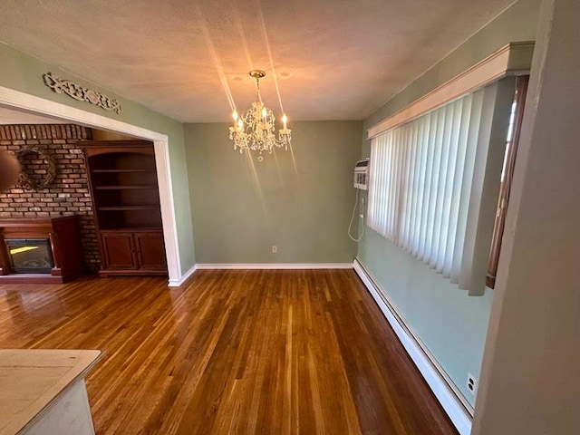 unfurnished dining area with a baseboard radiator, a chandelier, a fireplace, wood finished floors, and baseboards