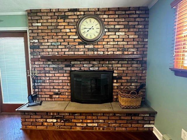 detailed view of wood finished floors, ornamental molding, a fireplace, and baseboards