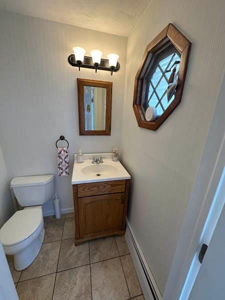bathroom with baseboard heating, tile patterned floors, toilet, vanity, and a textured ceiling