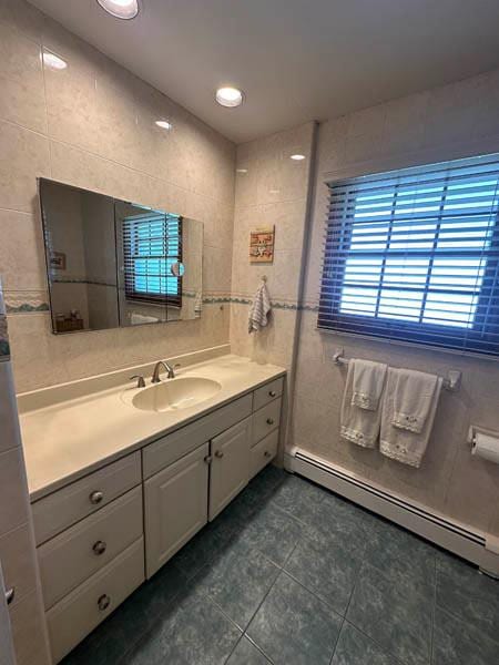 bathroom with tile patterned floors, a baseboard radiator, tile walls, and vanity