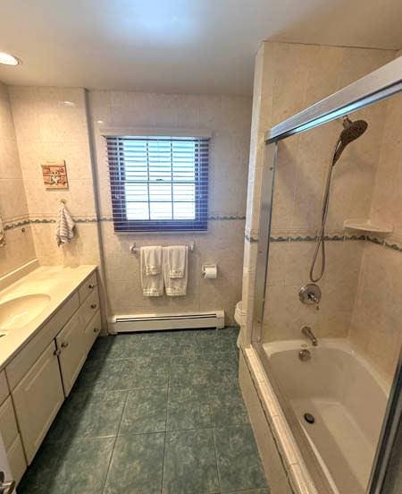 bathroom featuring a baseboard radiator, vanity, tub / shower combination, tile patterned floors, and toilet