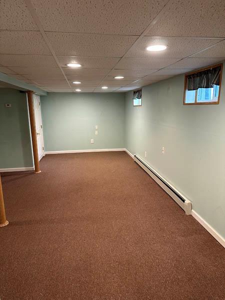 899 E Meadow Ave, North Bellmore, NY 11710 - below grade area with a baseboard radiator, dark carpet, baseboards, a paneled ceiling, and recessed lighting