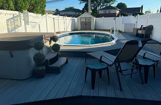 899 E Meadow Ave, North Bellmore, NY 11710 - view of swimming pool featuring a hot tub, a wooden deck, and a fenced backyard