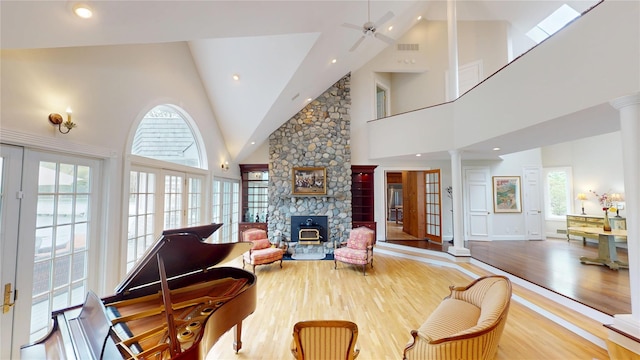 124 Montauk Hwy, Westhampton, NY 11977 - living room featuring decorative columns, high vaulted ceiling, wood finished floors, a stone fireplace, and ceiling fan