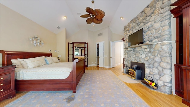 124 Montauk Hwy, Westhampton, NY 11977 - bedroom featuring a wood stove, light wood-type flooring, high vaulted ceiling, and a ceiling fan