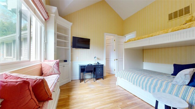 124 Montauk Hwy, Westhampton, NY 11977 - bedroom featuring wallpapered walls, wainscoting, light wood finished floors, and lofted ceiling