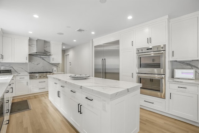 92 Random Farms Dr, Chappaqua, NY 10514 - kitchen featuring wall chimney range hood, appliances with stainless steel finishes, light wood finished floors, a center island, and tasteful backsplash