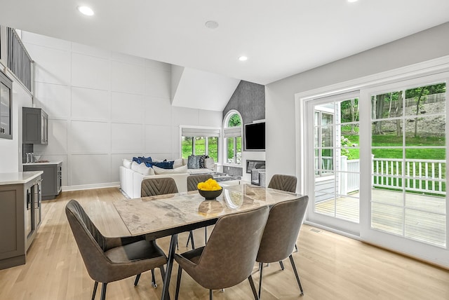 92 Random Farms Dr, Chappaqua, NY 10514 - dining space featuring light wood-style floors, recessed lighting, a decorative wall, a glass covered fireplace, and lofted ceiling