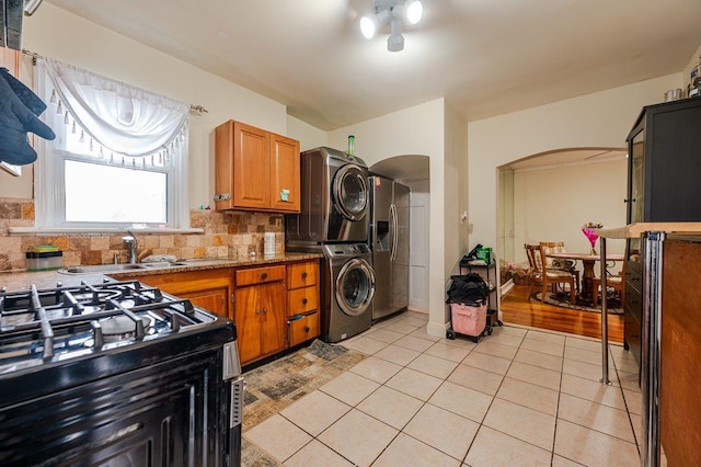 31 Thurman St, Yonkers, NY 10701 - kitchen with stacked washer and clothes dryer, arched walkways, range with gas stovetop, stainless steel fridge, and a sink