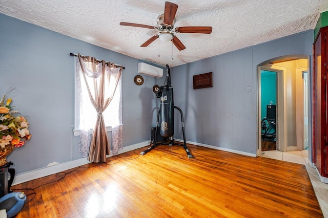 31 Thurman St, Yonkers, NY 10701 - exercise area featuring arched walkways, a wall unit AC, light wood-style floors, a textured ceiling, and ceiling fan