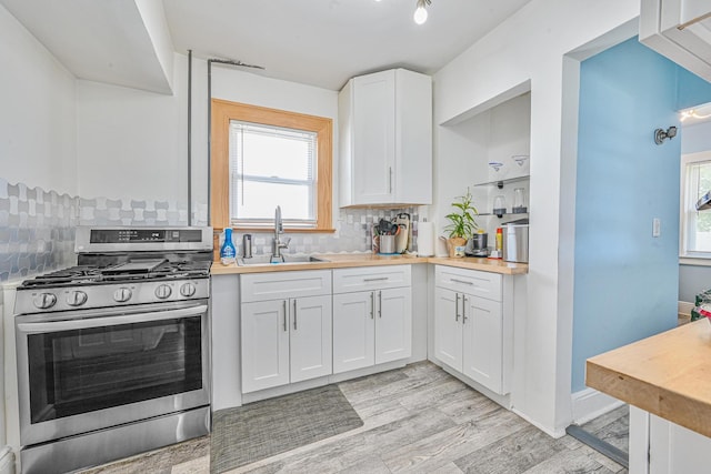 186-16 104th Ave, Saint Albans, NY 11412 - kitchen featuring stainless steel range with gas stovetop, a sink, decorative backsplash, white cabinets, and plenty of natural light