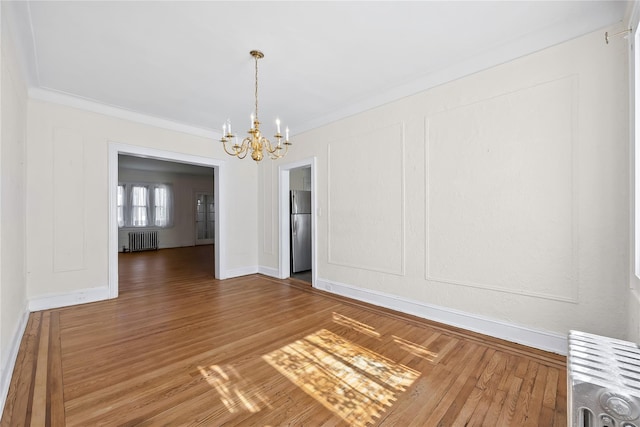 unfurnished dining area featuring radiator, a chandelier, ornamental molding, baseboards, and wood finished floors