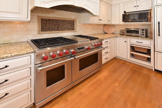 1515 Lowell Ave, New Hyde Park, NY 11040 - kitchen with range with two ovens, built in microwave, custom range hood, decorative backsplash, and light wood-type flooring