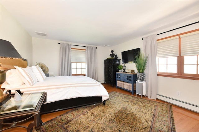1515 Lowell Ave, New Hyde Park, NY 11040 - bedroom featuring multiple windows, wood finished floors, and a baseboard radiator